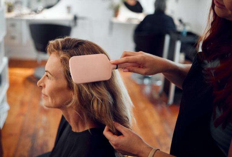 Parrucchiera che controlla la salute dei capelli in estate di una cliente durante una consulenza.