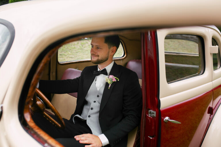 Sposo elegante in auto con look curato per matrimonio